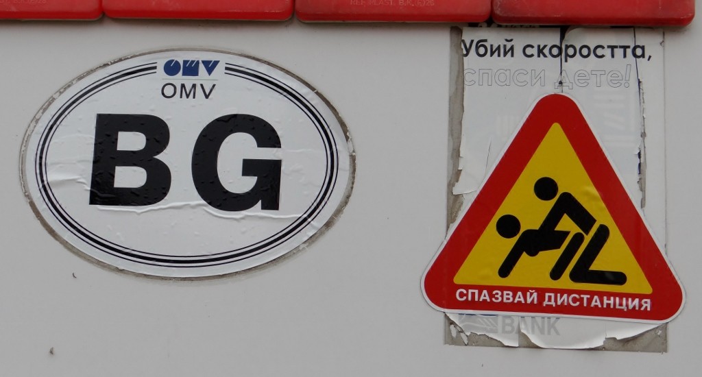 Not sure what the writing says, but it's a very unusual sticker for the back of a bus with Winnie the Pooh hanging from the rear view mirror!