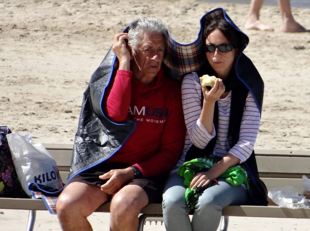 Couple on beach sheltering from wind