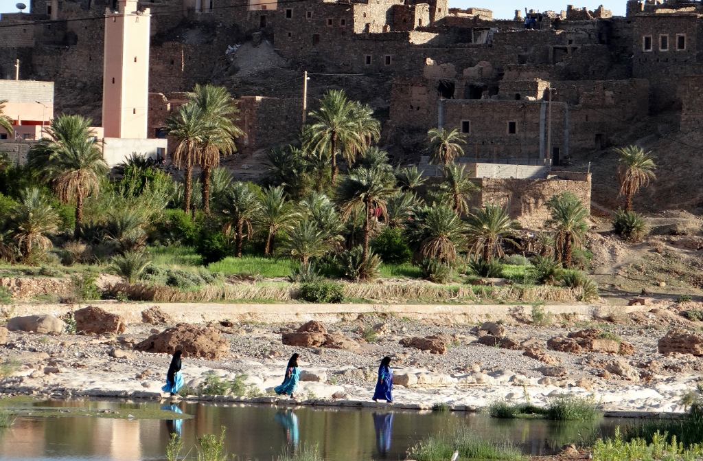 Ladies in colourful local dress crossing the river in Tata