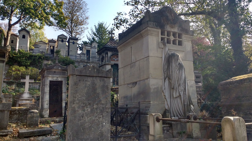 A robed figure reaching into a tomb at Pere Lachaise