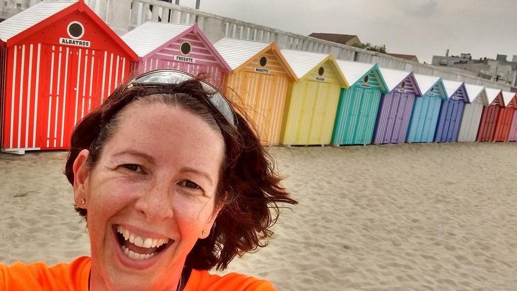 Woman running on a beach by huts in France at Stella Plage