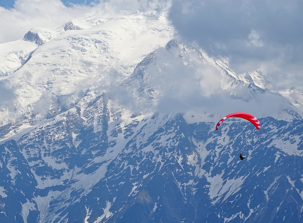 A paraglider flying with a backdrop of the mont blanc massif