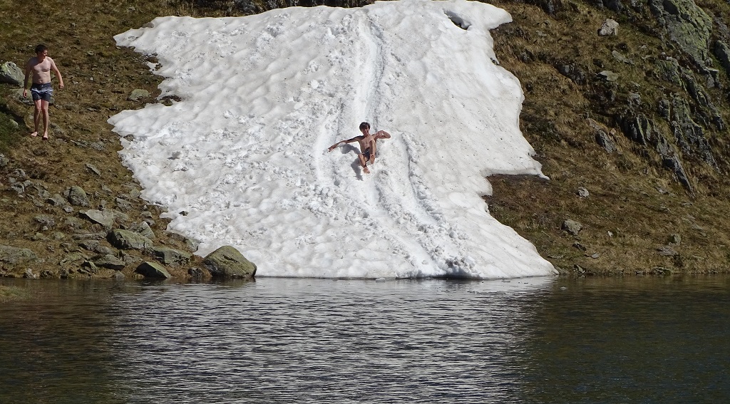 Kids sliding down snow into an ice-cold lake in Switzerland in June