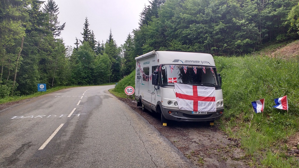 A motorhome covered in flags parked beside the road on the Col du Granier for a stage of the Critérium du Dauphiné