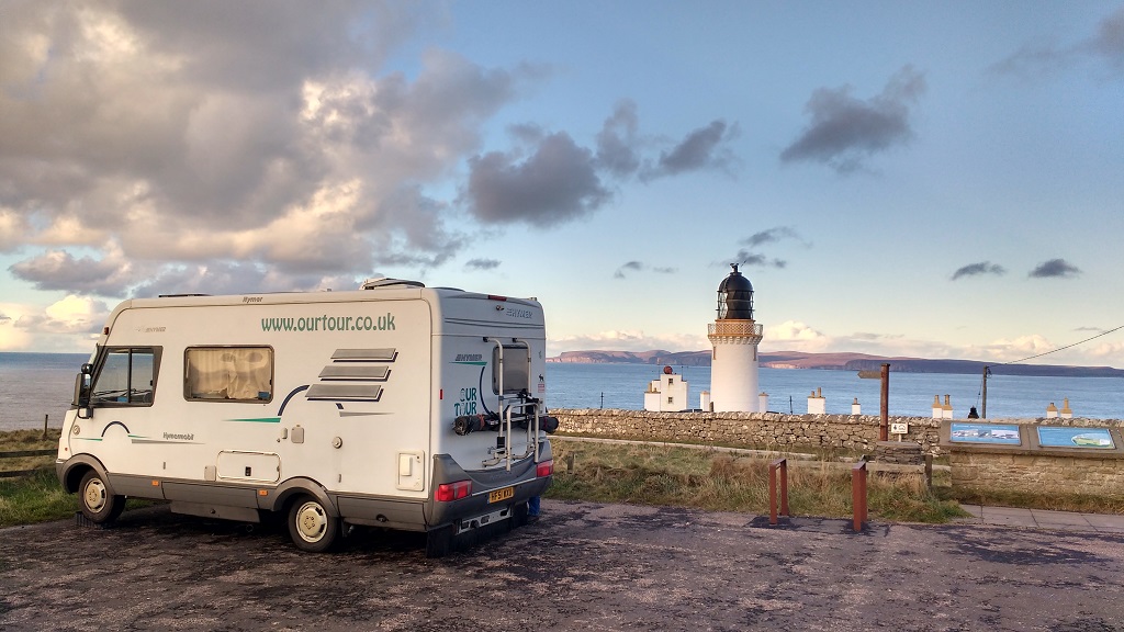 A motorhome Parked by the Dunnet Head Lighthouse, with the Orkney Islands in the background