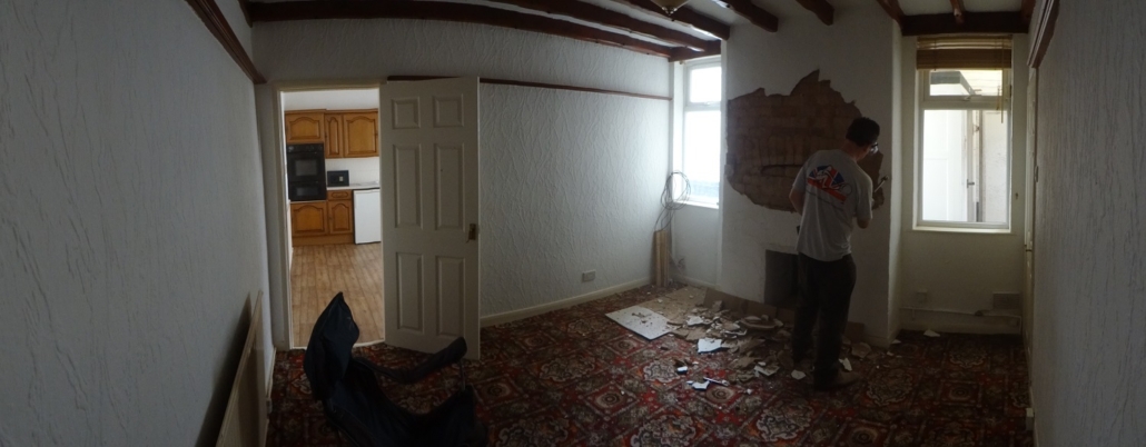 Removing the loose plaster from around the fireplace in the living room of The Butchers