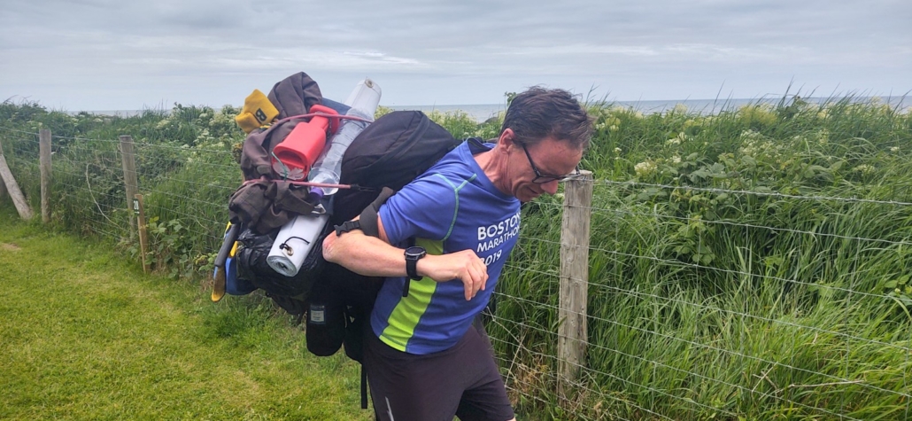 Man making a fool of himself trying to get a rucksack on