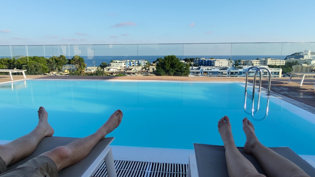 Feet on a sunlounger at a roof top pool