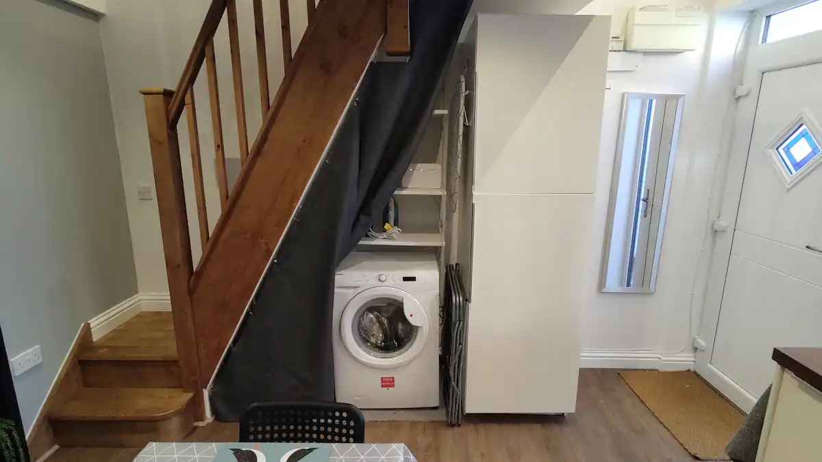Tucked-away utility area with a washing machine, iron and ironing board in the Kimberley Hideaway, AirBnB Nottingham