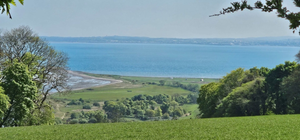 View from hill looking over loch and motorhome parking area with three motorhome dots in the distance.