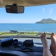 Feet on motorhome dashboard with view of sea and an island through the windscreen