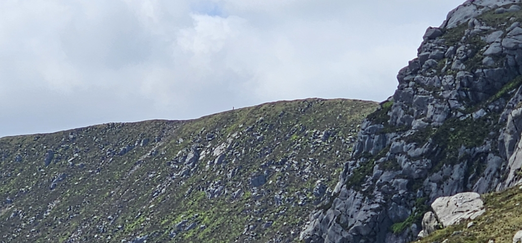 Tiny dot of a person on a ridge of rock