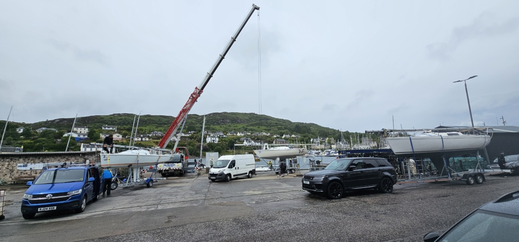 Yachts being lifted out of the water by a crane and put on the cradle to be towed