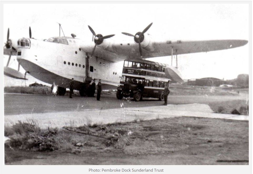Old photo of seaplane with double bus parked under its wing 
