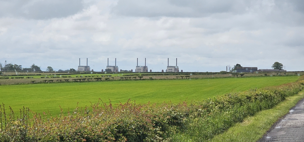 Four square buildings of old nuclear power station across a field