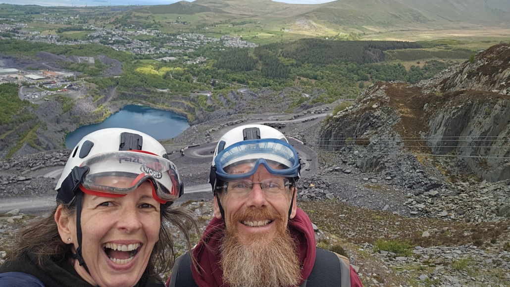 Ju and Jay in hard hats overlooking the quarry and zip wires in the background