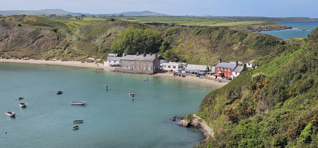 A small cove with blue sea and a couple of buildings just behind the beach.