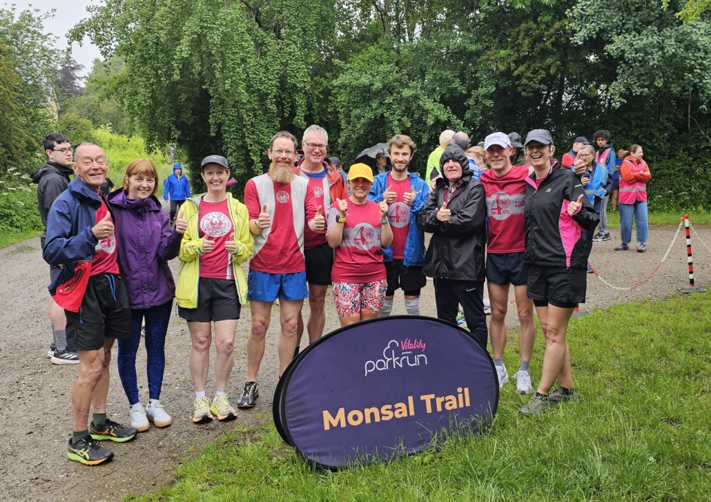 Group of runners in the rain by a parkrun sign